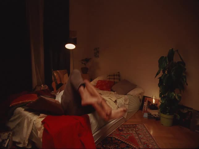 A man playfully hugs his female companion and pulls her onto a mattress with him
