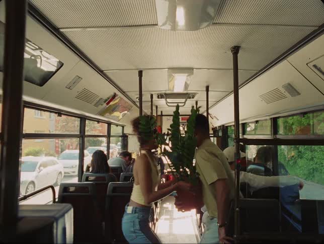 Couple carrying potted plant rush off stopped bus