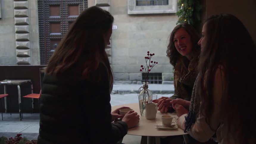 Three women sit at a patio table to talk and have drinks