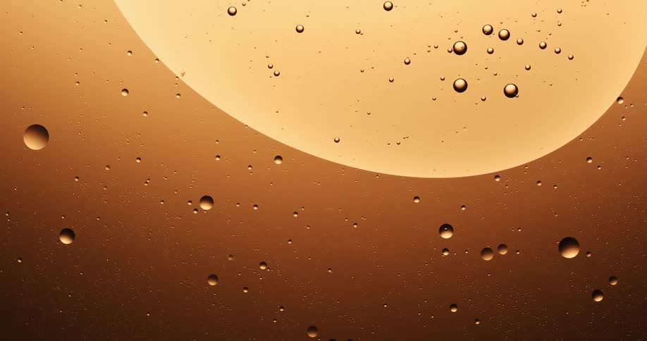 Many spheres are floating in a golden substance and there is a big orb with many smaller spheres inside floating down