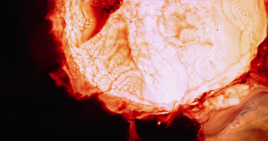 A light glows behind an orange liquid as it spreads out