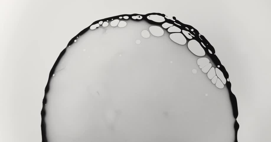 A black liquid grows darker as it spreads outward