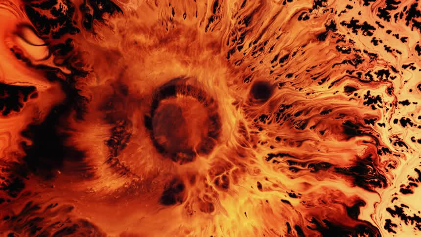 An organic orange substance with a round center is moving and spreading across the darkness