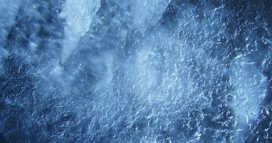 Light shines upon a cracked and textured icy surface as bubbles move below
