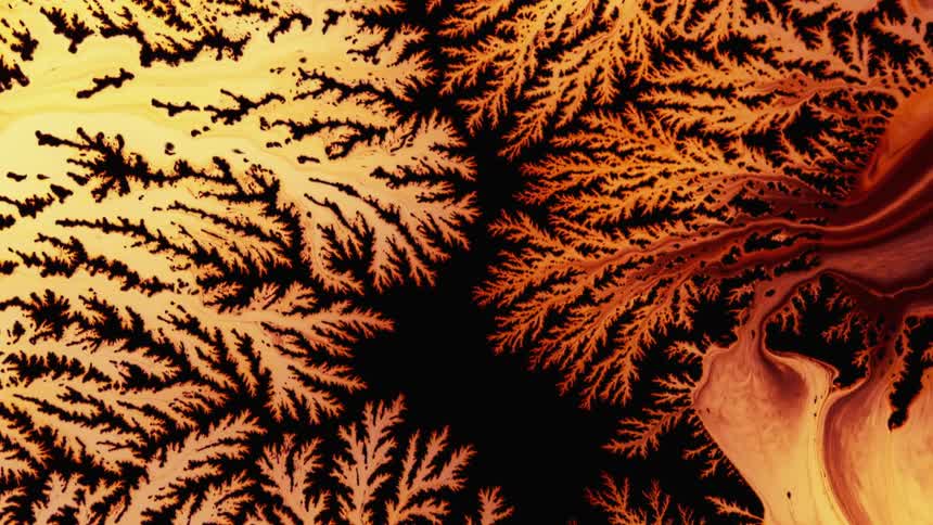 Red liquid flows and swirls into spiky texture and pattern