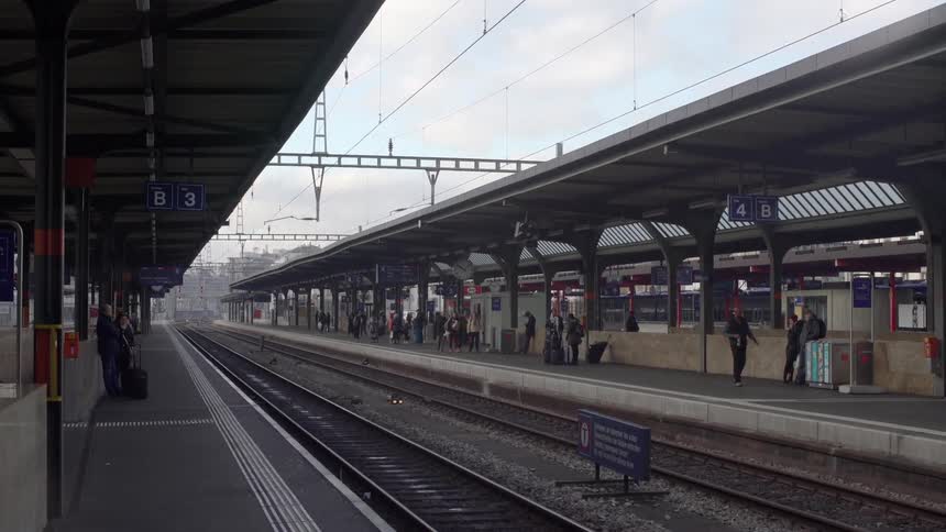 People mingle near the tracks at a train station