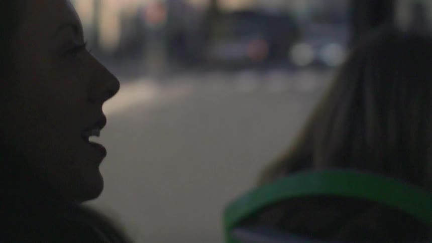 A woman riding public transit is speaking and smiling