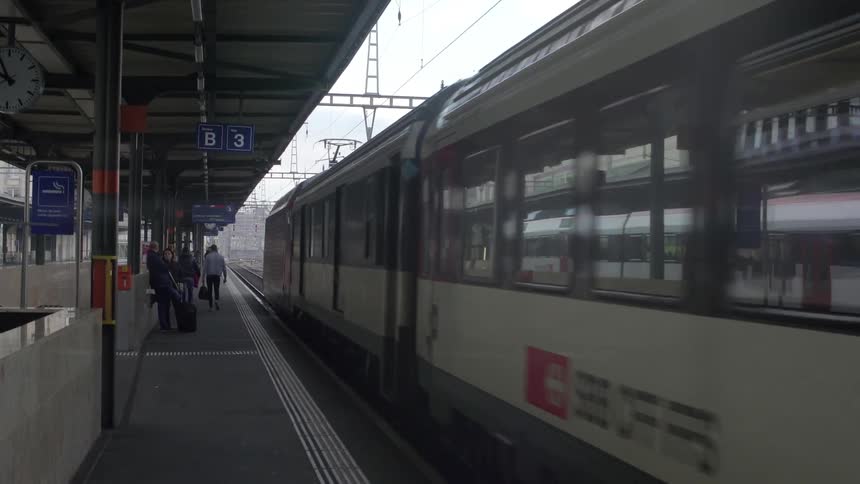 A train moves into a station with people waiting