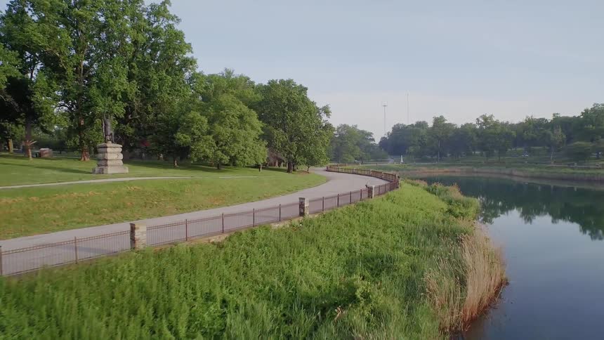 People travel along a winding road by a lake on a sunny day