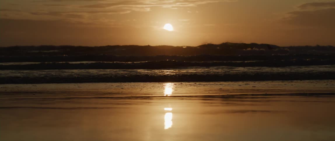 Sun above the horizon reflected in the ocean and on the sand