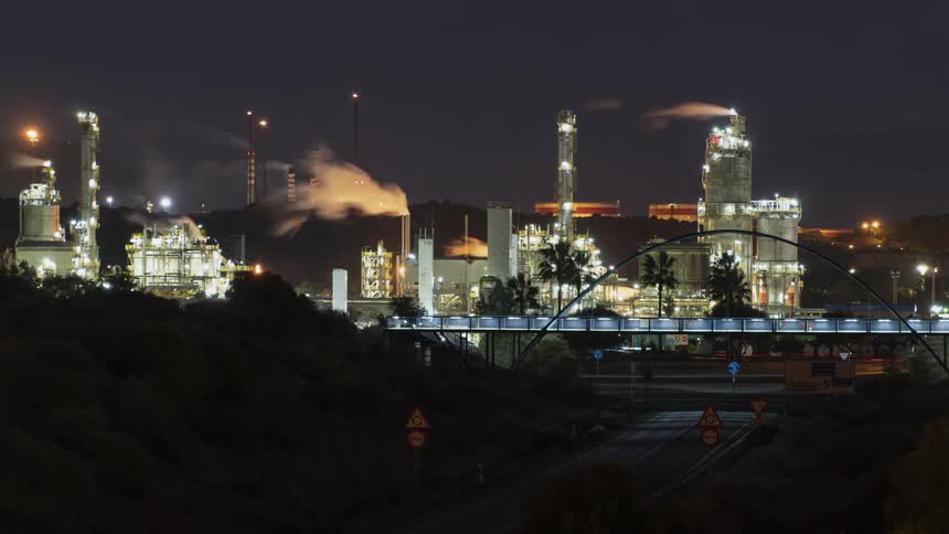 Time lapse of traffic passing below a bridge next to a powerplant