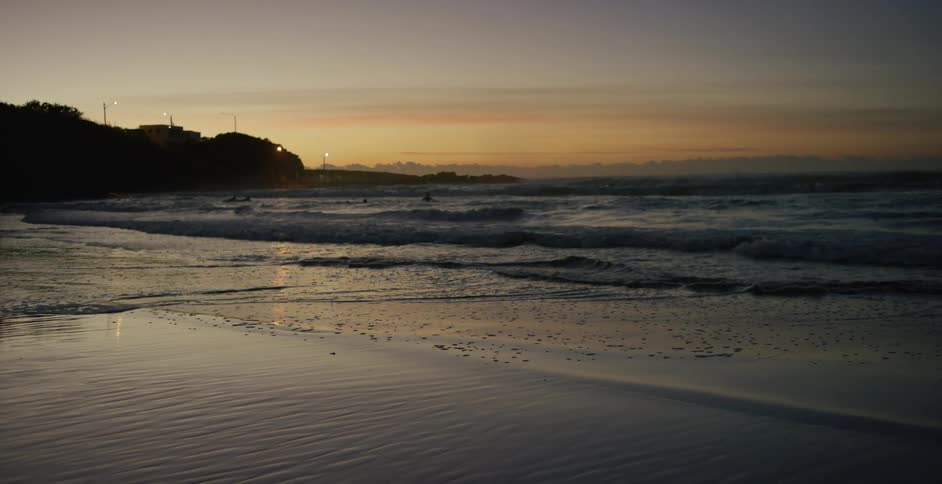 Ocean waves break against the shore at sunset