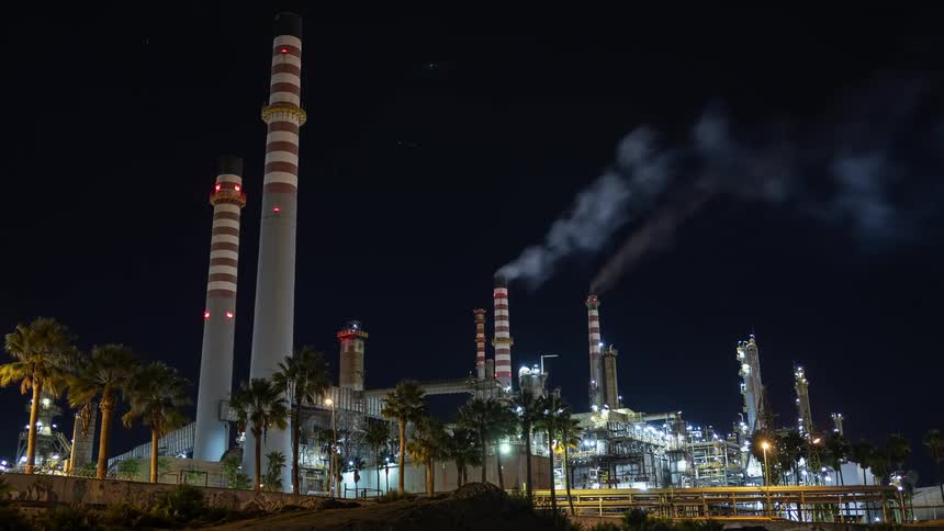 Tall factory chimneys pollute the air at night time