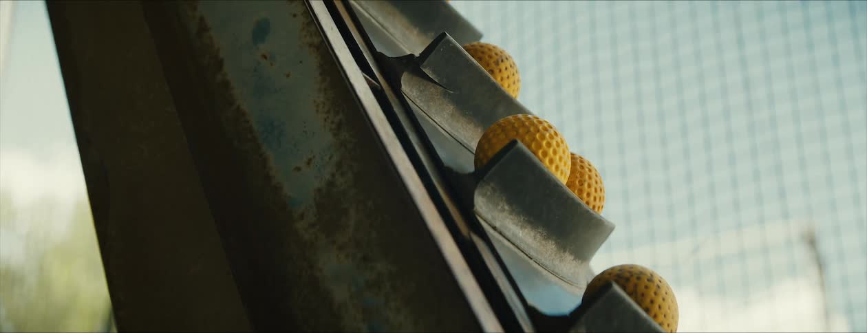 Yellow balls are moving up the conveyor with a net in the background