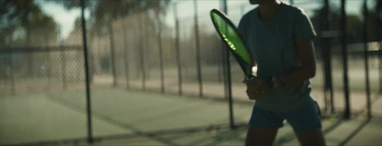 A black woman is playing tennis outdoors in the middle of the day