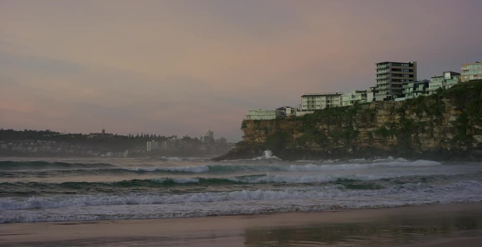 Ocean waves gently crashing on the coast next to a coastal city on the cliffs