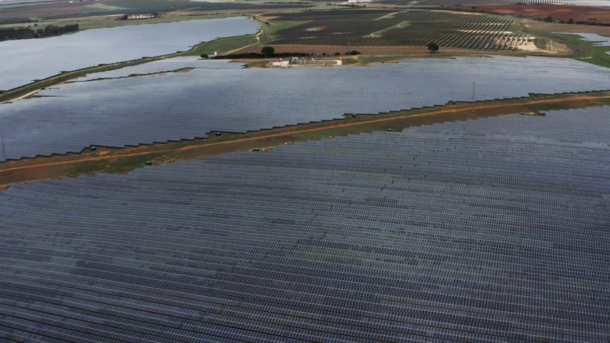 A road cuts through a vast solar farm in the countryside during the day