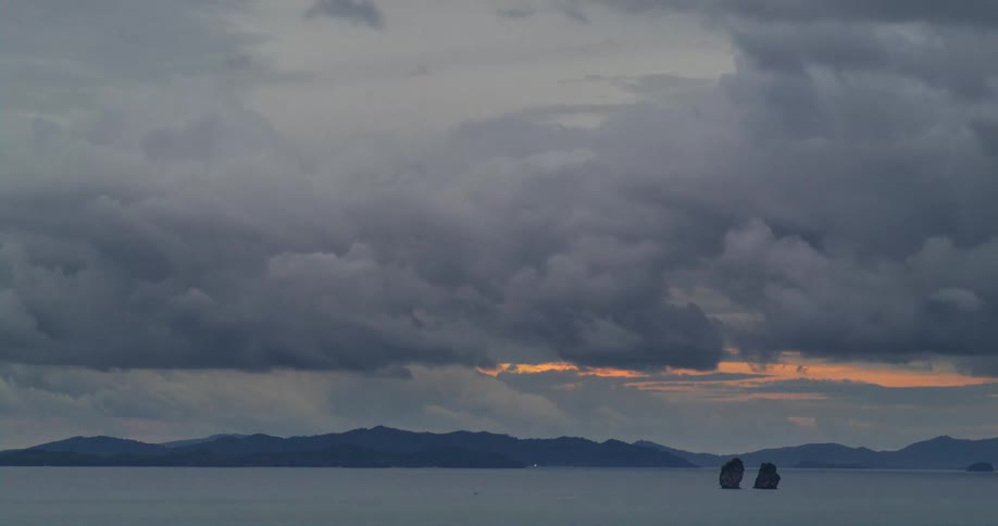 Clouds move right to left across the sky with a mountain range in the distance