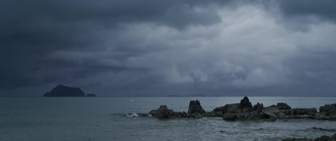 Dark clouds over the ocean as waves roll in to the shore