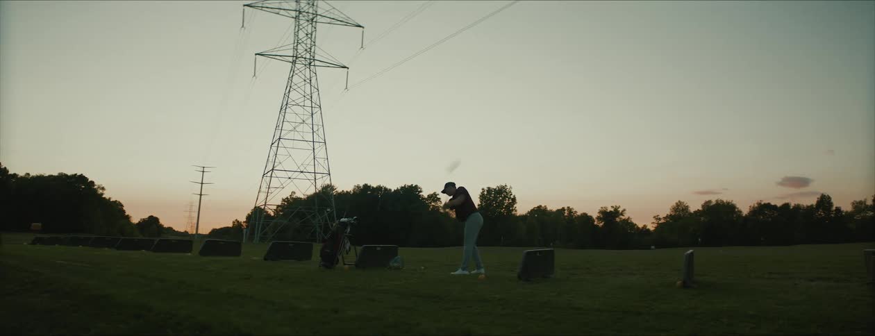 Golfer takes swing on golf course under power lines
