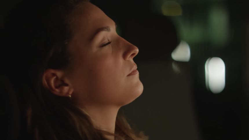 A woman is sitting indoors during the night time