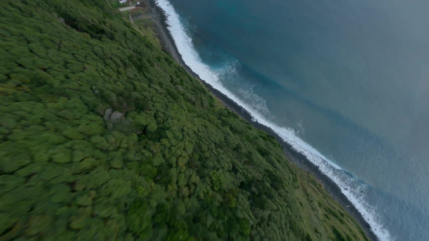 A cliff covered in vegetation looms over the ocean during the day
