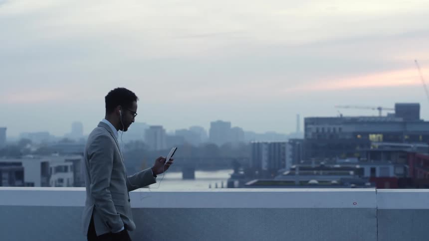 Man stands talking on smartphone with fog covered river and city in the background