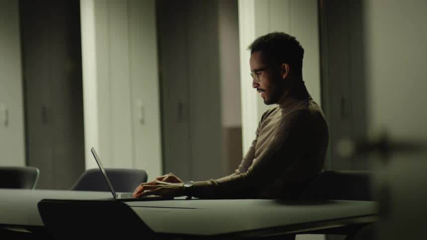 Young man sitting at a desk on the office meeting room working on a laptop