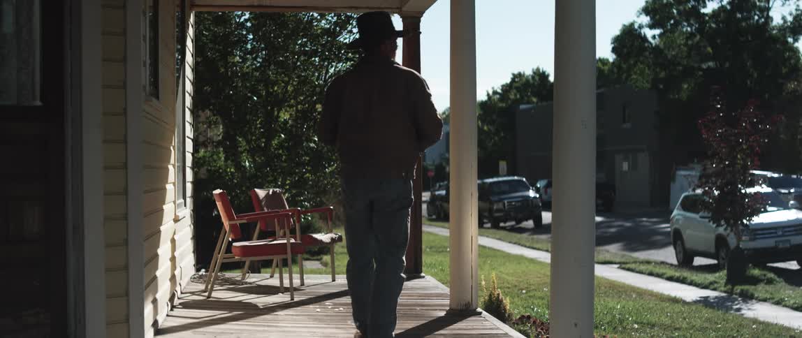 A man picks up the paper form his porch