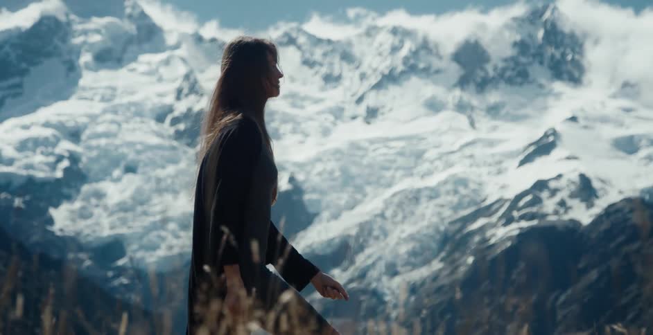 A woman is walking outdoors near mountains