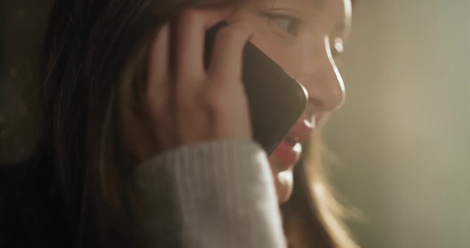 A young woman smiles and laughs as she talks on a cell phone