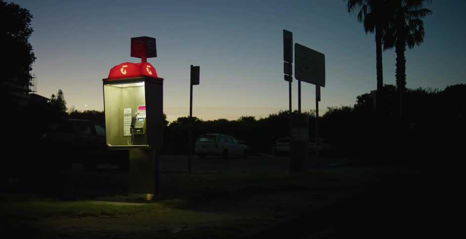 Lit up pay phone in a parking lot at night