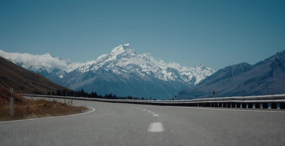 Snow covered mountain peak across the horizon behind the highway guardrail