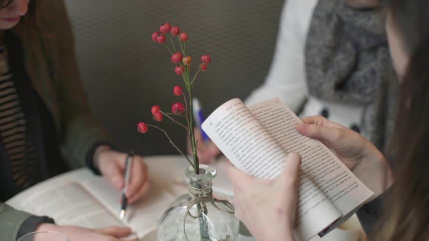 Women sit at a table and read