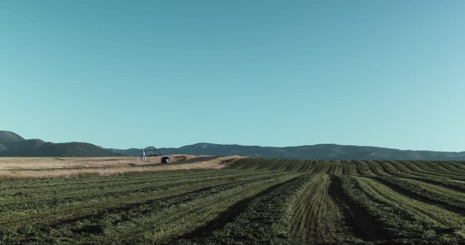 Car drives along highway passing fields full of crops with mountains on the horizon