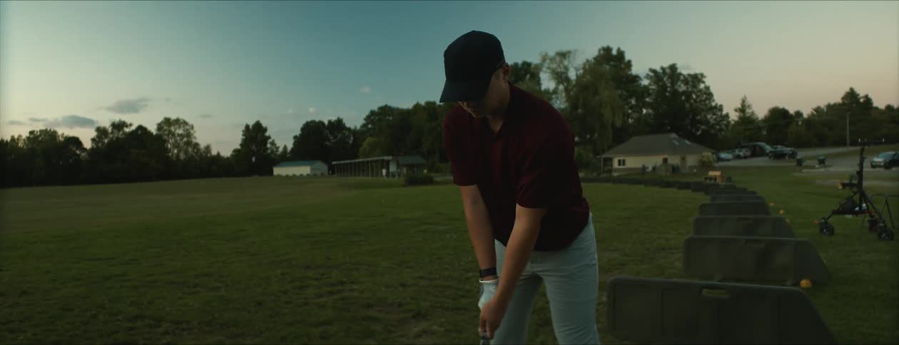 A male swings a golf club as he hits a ball