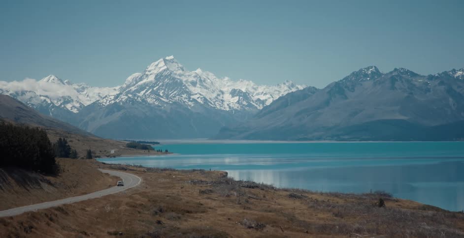 Vehicle driving on a road near a lake in the mountains at morning