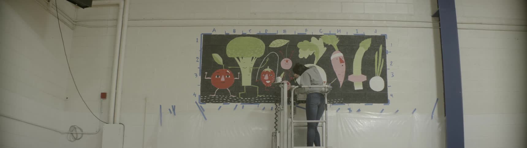 A woman is painting a mural on a wall