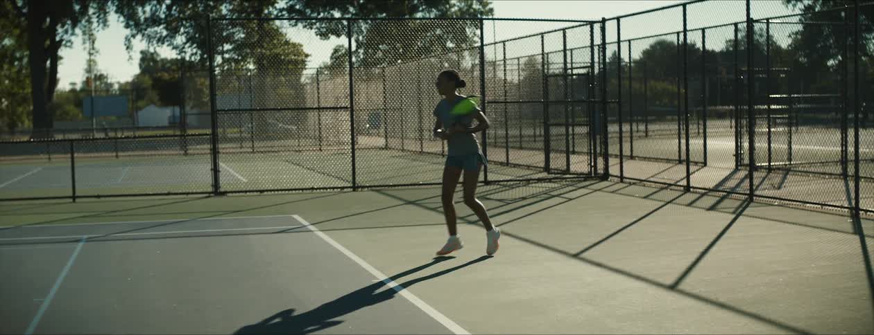 Young female tennis player returns a ball on a court at morning