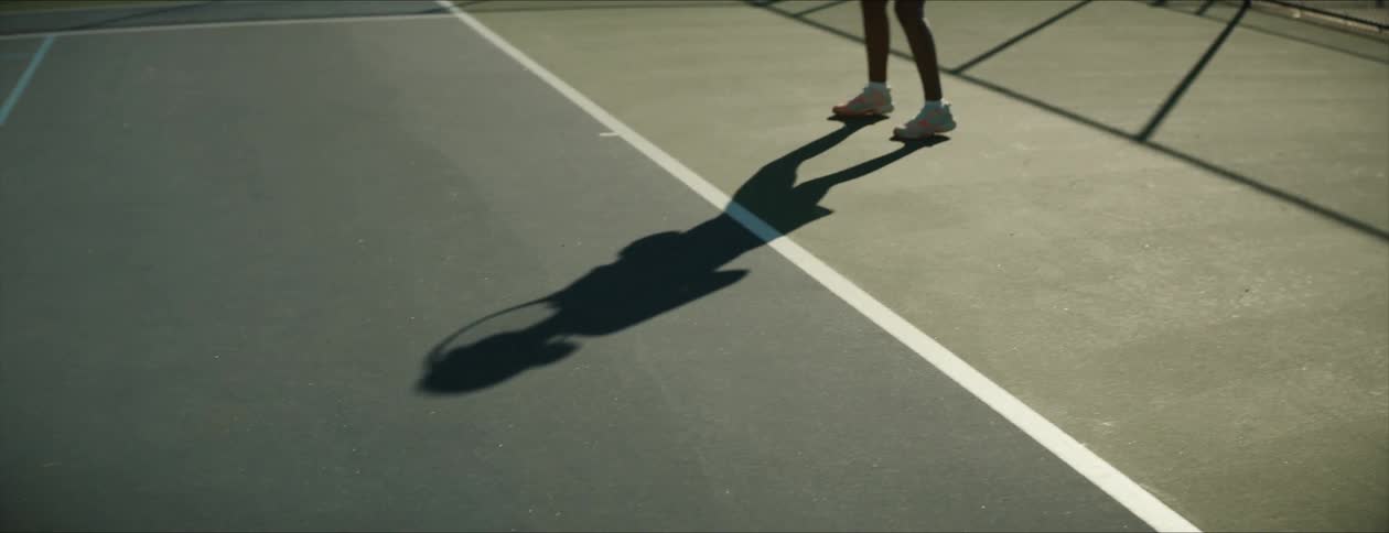 A young black woman is playing tennis in the day time