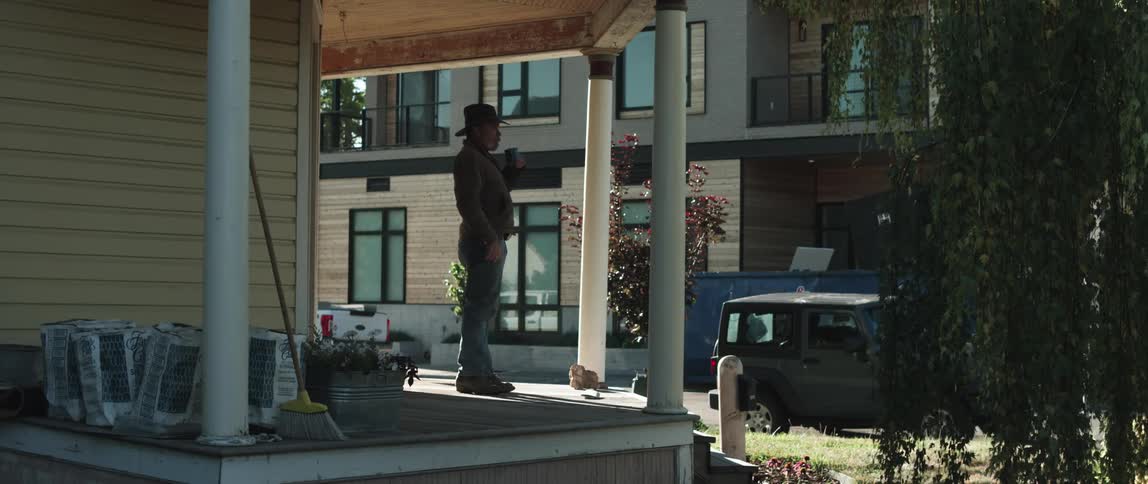 An older white man is outside of his house in the middle of the day time
