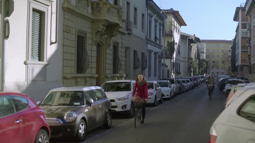 People ride bikes down a narrow city street