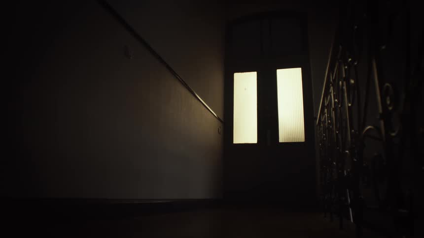 A light comes on behind a door in a dark corridor