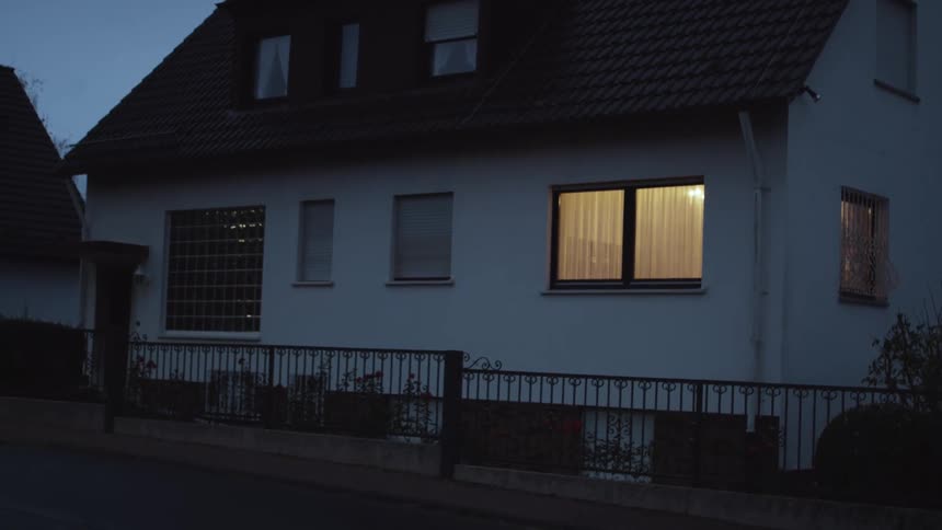 The outside of a black and white house as a light turns off