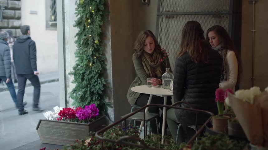 Three women sit at a patio table to talk and have drinks