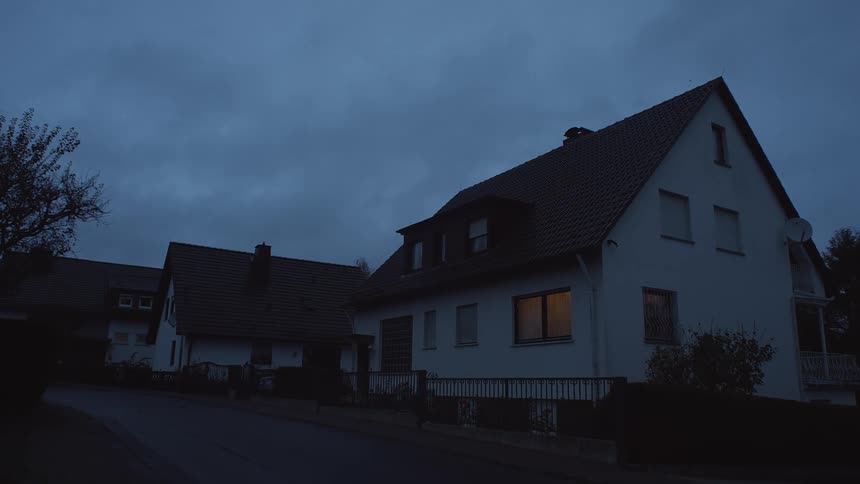 Lights turning on the window of a house in a calm neighborhood at morning