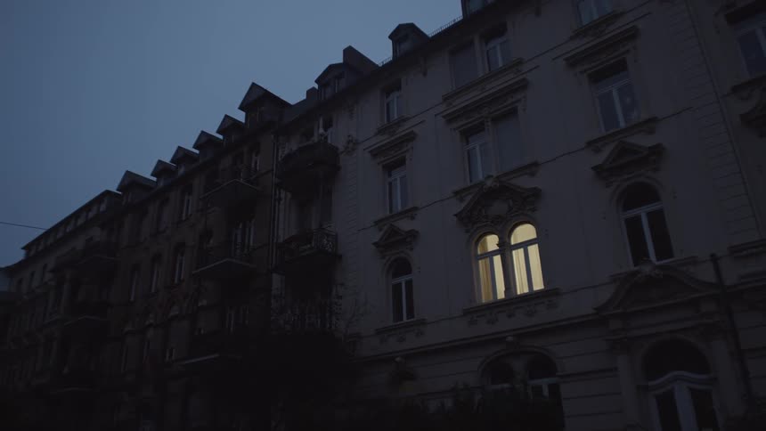 The outside of an apartment building as a light turns on in one of the rooms