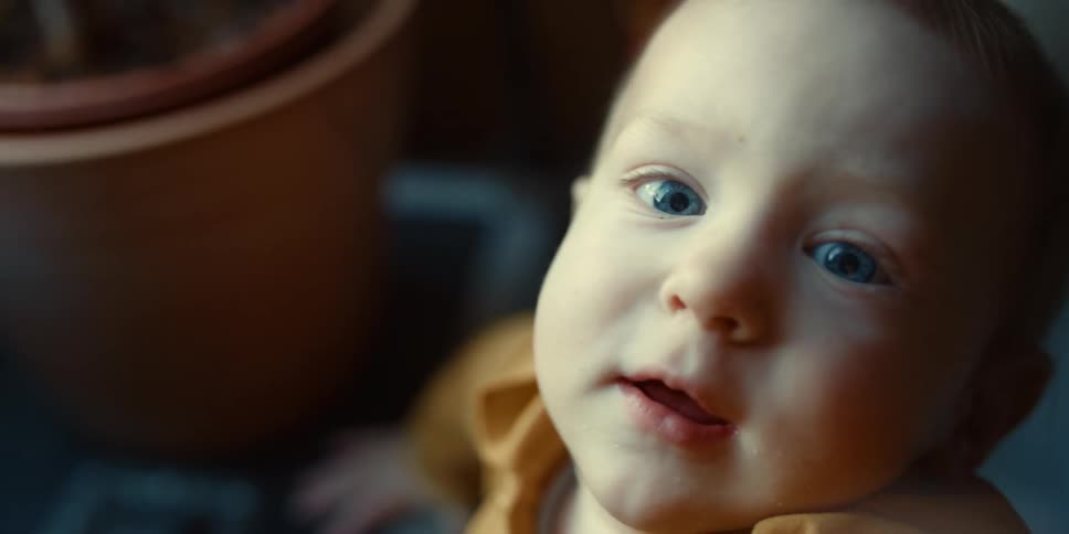 Toddler boy reaches out to camera in room
