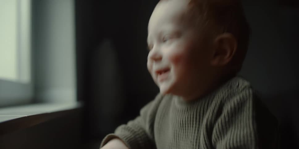 Happy baby jumps up and down while looking out a window at home