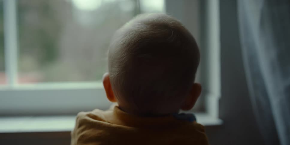 A small child standing while looking out the window